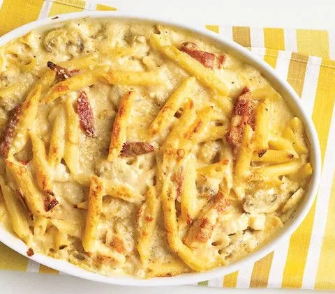Martha Stewart baked penne with chicken and sun-dried tomatoes in a white oval baking dish with golden cheese on top
