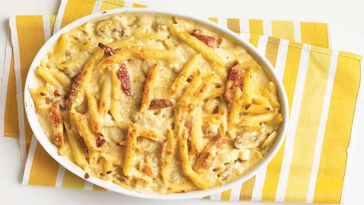 Martha Stewart baked penne with chicken and sun-dried tomatoes in a white oval baking dish with golden cheese on top