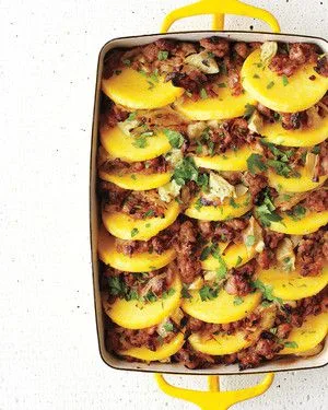 Martha Stewart baked polenta with sausage and artichoke hearts in a baking dish with sliced polenta rounds and parsley