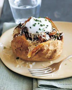 Martha Stewart baked potatoes with sauteed mushrooms and yogurt topped with grated cheddar and chives on a cream plate