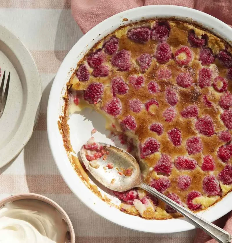 Martha Stewart baked raspberry custard in a white pie plate with a golden top, served with whipped cream