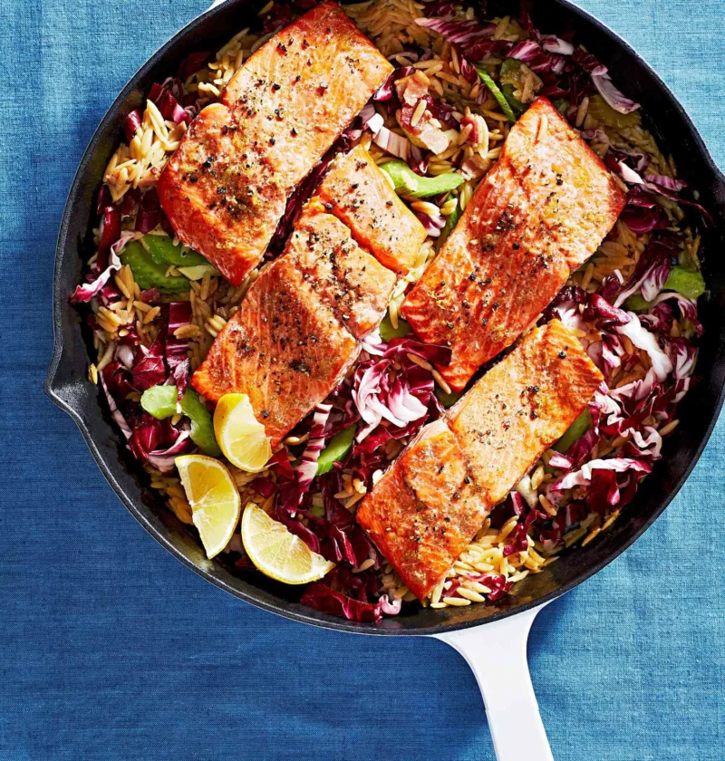 Martha Stewart baked salmon with creamy orzo in a skillet with radicchio and lemon wedges