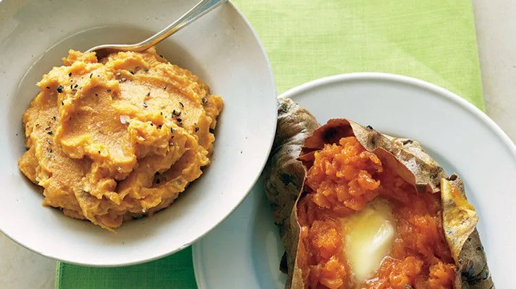 Martha Stewart baked sweet potatoes with brown sugar, one mashed in a white bowl and one split open with melting butter