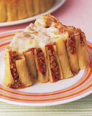Martha Stewart baked ziti with ground beef cut into a wedge, showing upright ziti tubes filled with meat sauce under melted mozzarella