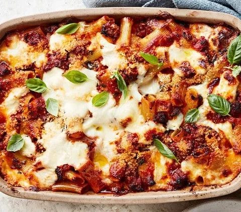 Martha Stewart baked ziti with sausage and bechamel in a baking dish topped with melted mozzarella and fresh basil leaves