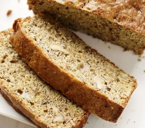 Sliced Martha Stewart banana bread with walnuts and flaxseed on a white plate