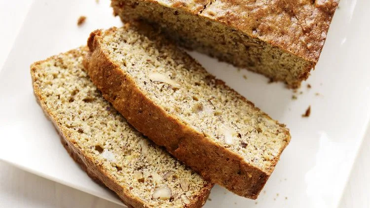 Sliced Martha Stewart banana bread with walnuts and flaxseed on a white plate