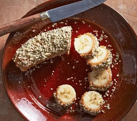 Martha Stewart banana energy bites: a banana coated in nut butter and hemp seeds, sliced into rounds on a brown plate with a knife