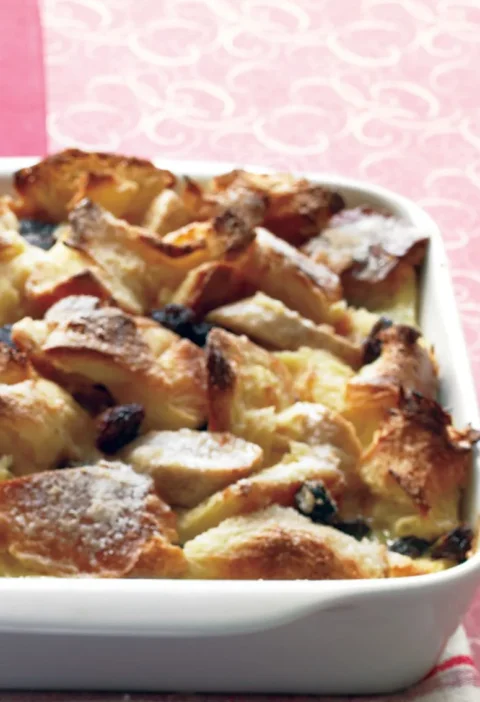 Martha Stewart banana-raisin bread pudding baked golden in a white rectangular dish with raisins peeking through