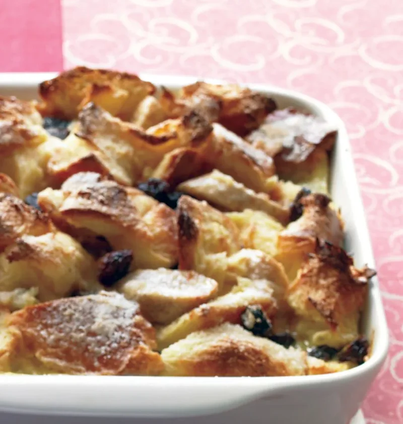 Martha Stewart banana-raisin bread pudding baked golden in a white rectangular dish with raisins peeking through