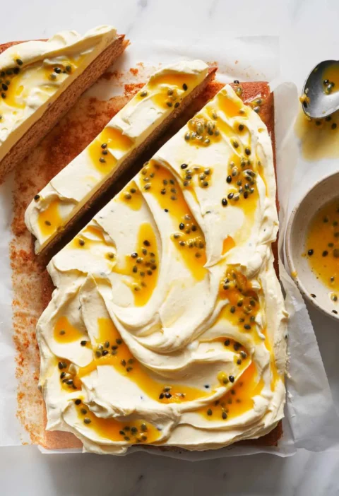 Martha Stewart banana sheet cake with passion-fruit frosting swirled with passion-fruit pulp and cut into slices on parchment