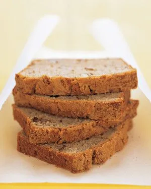 Four slices of Martha Stewart banana-walnut loaf stacked on white parchment paper