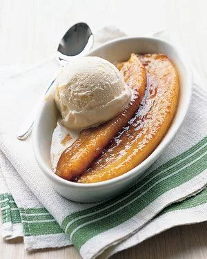 Martha Stewart bananas foster split with caramelized banana halves and a scoop of vanilla ice cream in a white oval dish