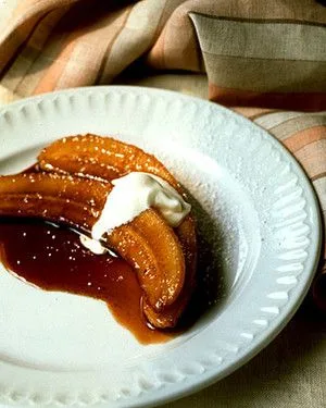 Martha Stewart bananas in brown sugar and rum glazed in caramel sauce with a dollop of creme fraiche on a white plate