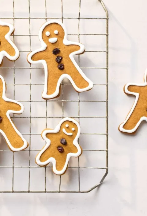 Martha Stewart basic gingerbread cookies shaped like gingerbread people with currant buttons and white icing outlines on a wire cooling rack