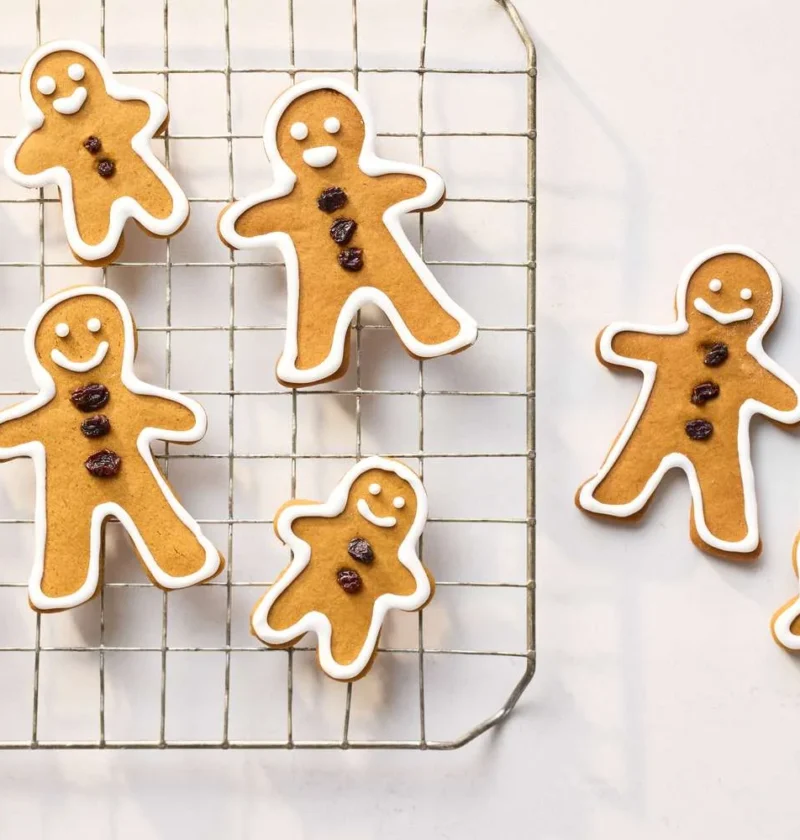 Martha Stewart basic gingerbread cookies shaped like gingerbread people with currant buttons and white icing outlines on a wire cooling rack