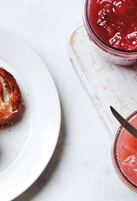 Martha Stewart basic jam in glass jars next to toast spread with orange and blackberry jam