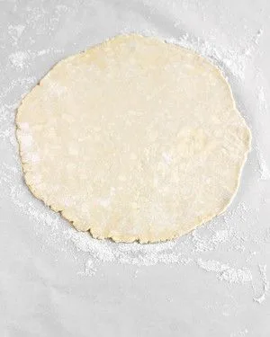 Martha Stewart basic pie crust dough rolled into a round on floured parchment paper