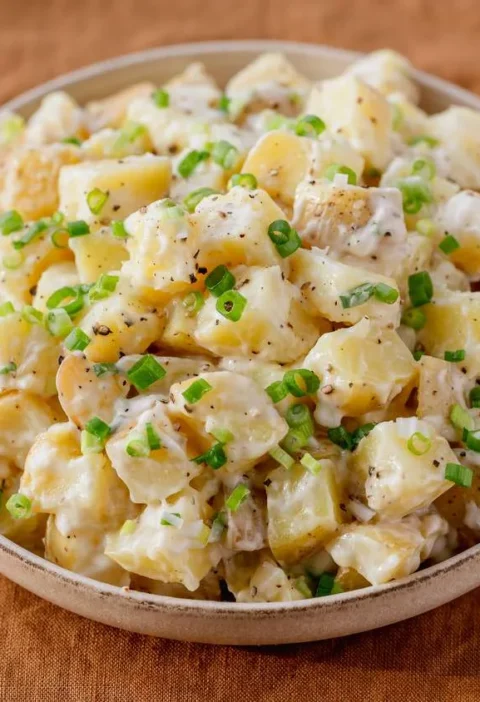Martha Stewart basic potato salad with creamy Yukon gold potato cubes and sliced scallions in a shallow bowl
