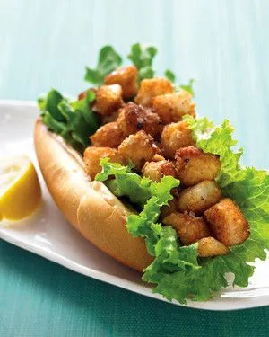 Martha Stewart bay-scallop po' boy with spicy mayo, golden fried scallops piled on lettuce in a bun with a lemon wedge
