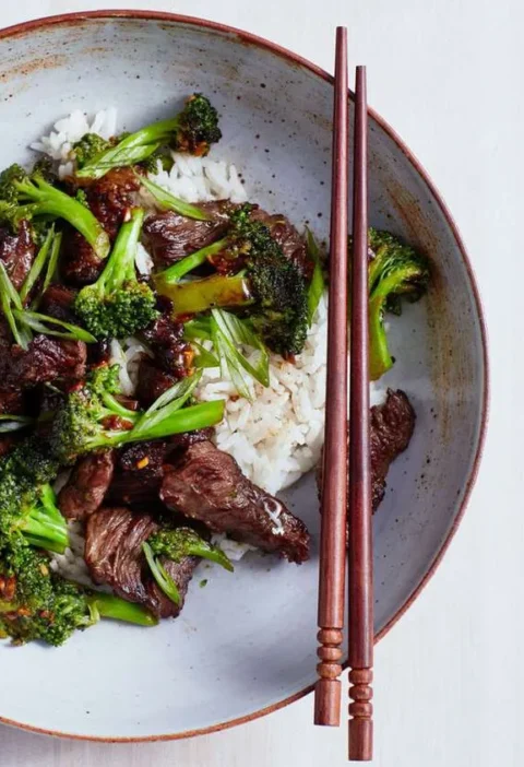 Martha Stewart beef and broccoli with black-bean garlic sauce served over white rice in a shallow bowl with chopsticks
