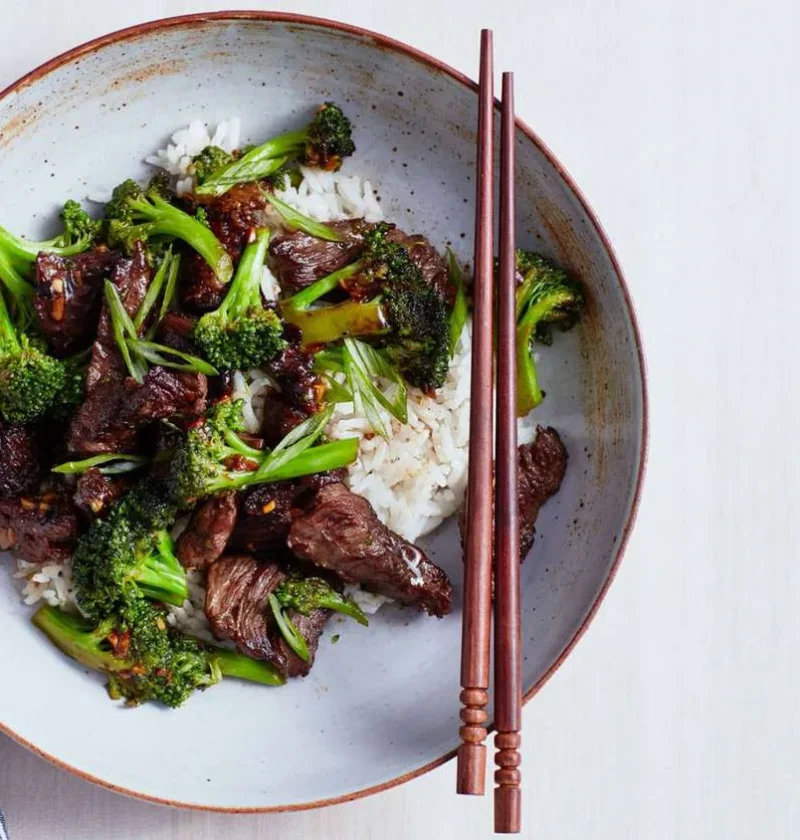 Martha Stewart beef and broccoli with black-bean garlic sauce served over white rice in a shallow bowl with chopsticks
