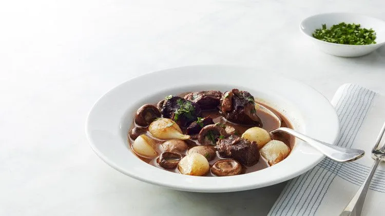 Martha Stewart beef Bourguignon in a white bowl with tender beef, glazed pearl onions and mushrooms in a red wine sauce