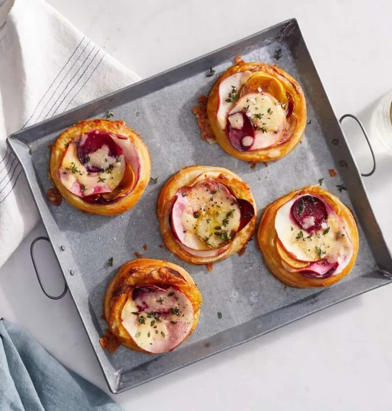 Martha Stewart beet, cheddar and apple tarts with sliced beet and apple on golden puff pastry on a metal serving tray