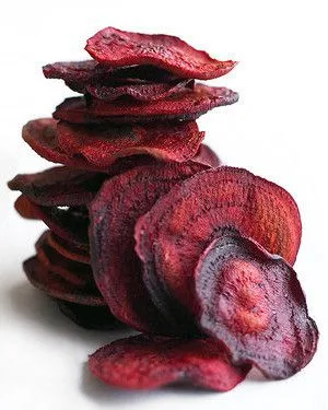 Stack of crisp baked Martha Stewart beet chips in deep magenta red on a white background