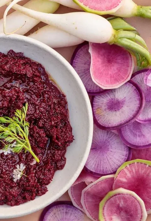 Martha Stewart beet muhammara in a white bowl with cilantro and sliced radishes alongside