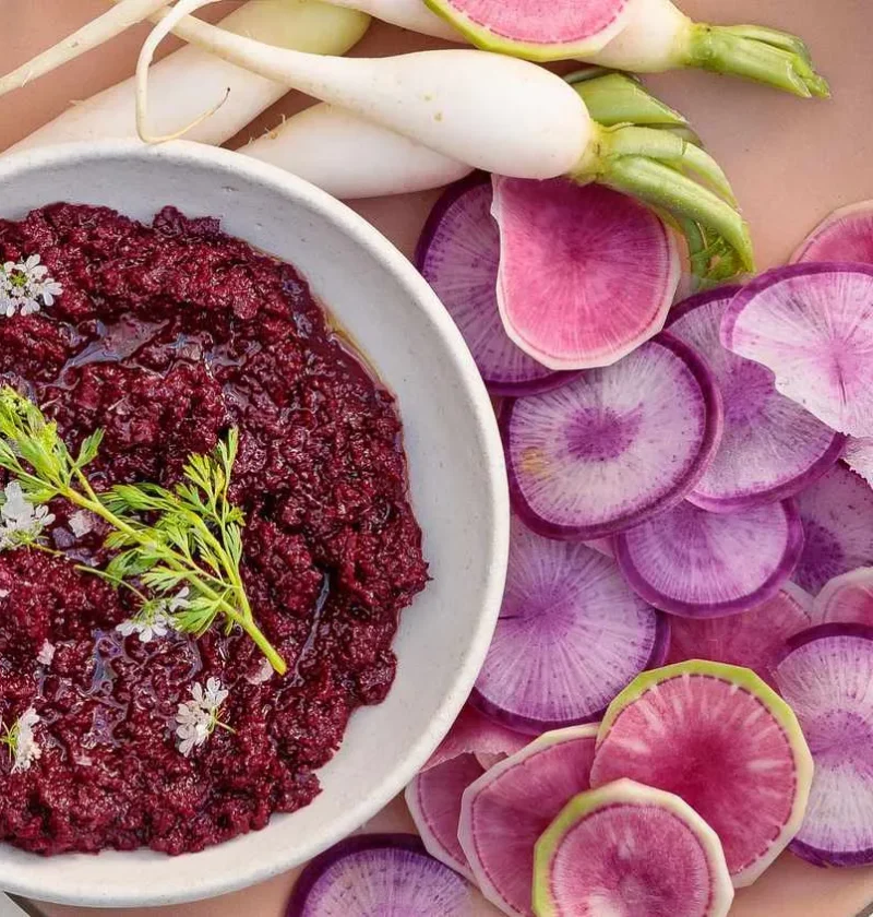 Martha Stewart beet muhammara in a white bowl with cilantro and sliced radishes alongside
