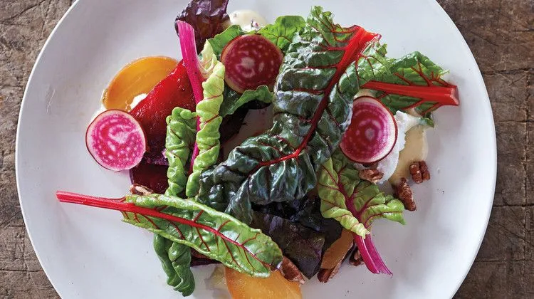 Martha Stewart beet salad with honey-lavender dressing, with roasted yellow and red beets, chard, pecans and thin Chioggia beet slices on a white plate