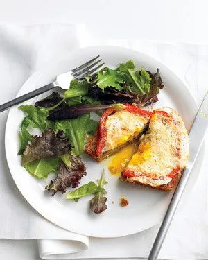 Martha Stewart bell pepper egg-in-a-hole on multigrain toast with a runny yolk beside a mixed green salad on a white plate