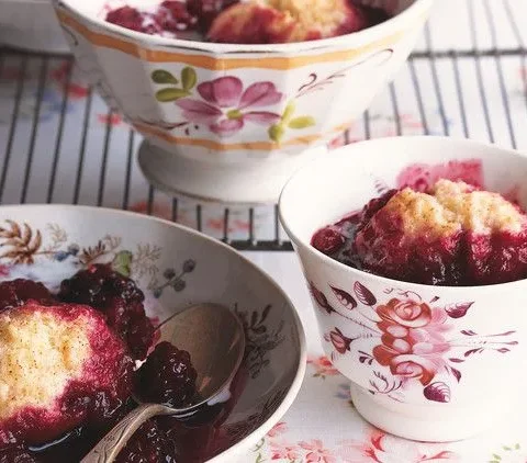 Martha Stewart berry grunt with golden dumplings over raspberries and blackberries in floral bowls with a drizzle of cream