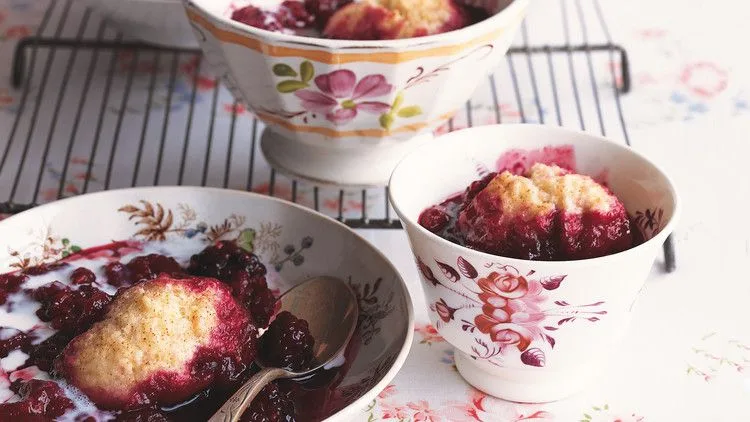 Martha Stewart berry grunt with golden dumplings over raspberries and blackberries in floral bowls with a drizzle of cream