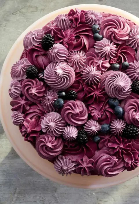 Martha Stewart berry layer cake topped with burgundy buttercream swirls, rosettes and fresh blackberries and blueberries