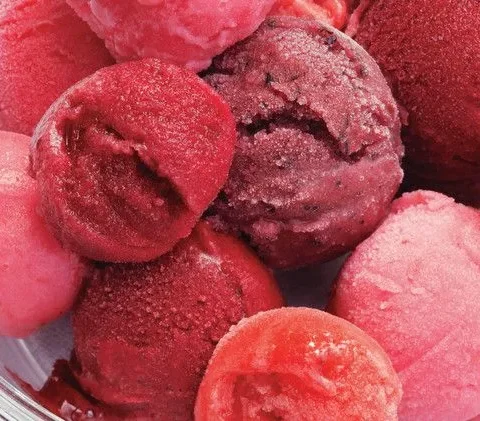 Scoops of pink, red and dark purple Martha Stewart berry sorbet piled in a clear glass bowl