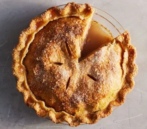 Martha Stewart best apple pie with a golden double crust, vents and a slice cut out in a glass pie dish