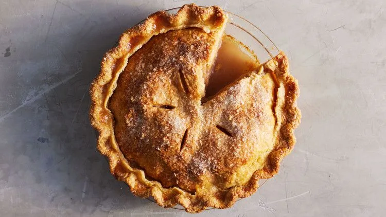 Martha Stewart best apple pie with a golden double crust, vents and a slice cut out in a glass pie dish