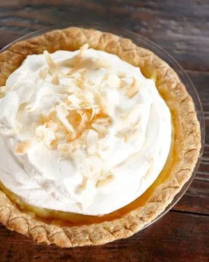 Martha Stewart best coconut cream pie topped with whipped cream and toasted coconut flakes in a golden crust