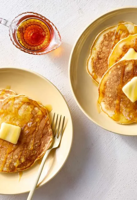 Martha Stewart best quick pancakes stacked on cream plates with butter pats and maple syrup