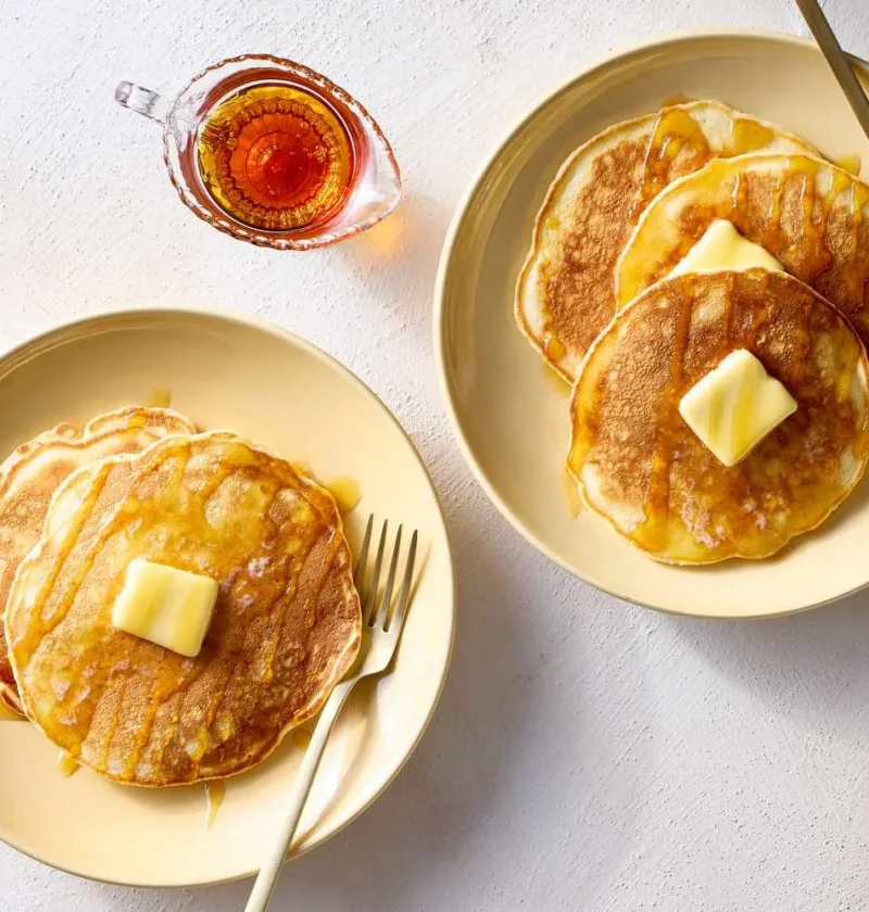 Martha Stewart best quick pancakes stacked on cream plates with butter pats and maple syrup