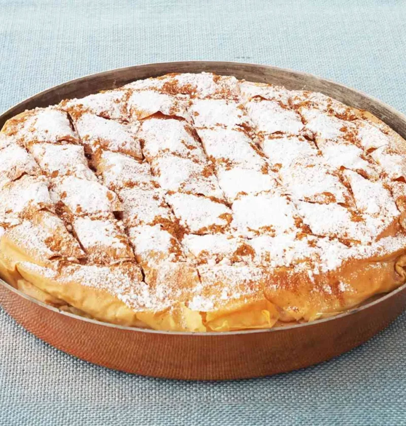 Martha Stewart bisteeya, a golden phyllo pie scored in a diamond pattern and dusted with confectioners' sugar in a round copper pan