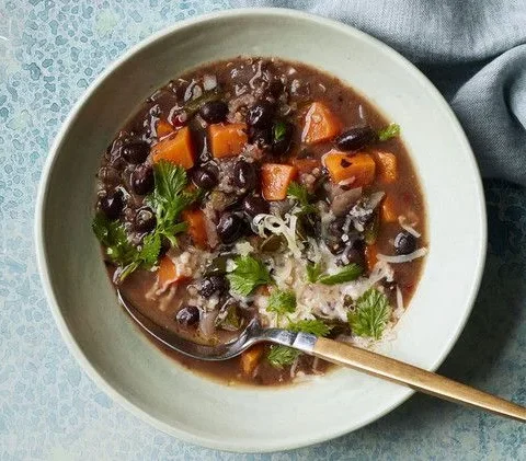 Martha Stewart black-bean and sweet-potato stew in a pale bowl topped with cilantro and shredded cheddar