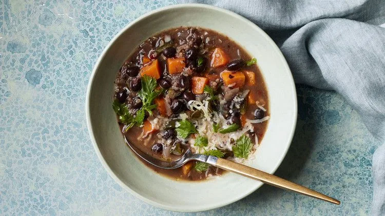 Martha Stewart black-bean and sweet-potato stew in a pale bowl topped with cilantro and shredded cheddar