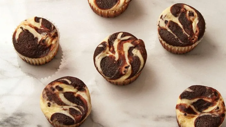 Martha Stewart black bottom cupcakes with a marbled chocolate and cream cheese top on a white marble surface