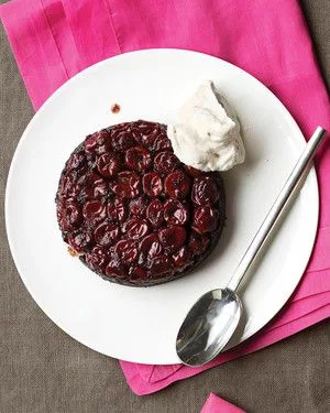 Martha Stewart Black Forest upside-down cake topped with glossy sour cherries and a dollop of rum whipped cream on a white plate