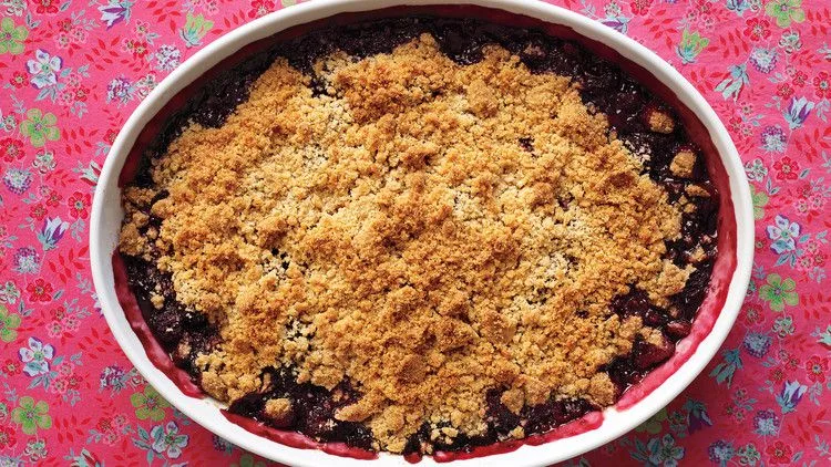 Martha Stewart blackberry crisp with a golden brown crumb topping in an oval baking dish on a floral tablecloth