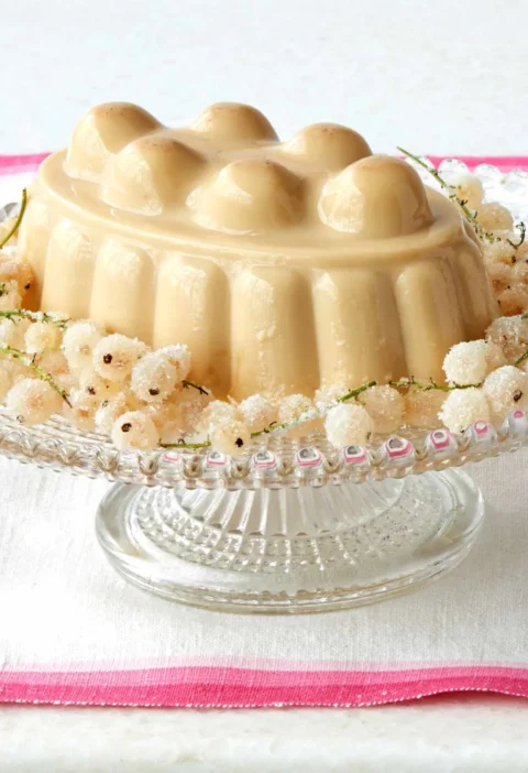 Martha Stewart blancmange unmolded on a glass cake stand, surrounded by sugared white currants