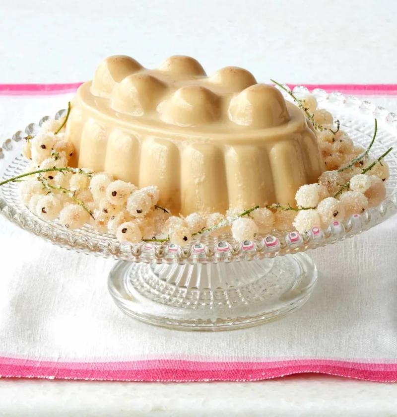 Martha Stewart blancmange unmolded on a glass cake stand, surrounded by sugared white currants